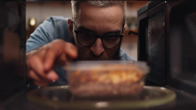 man putting leftovers in the fridge
