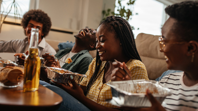 people laughing and eating takeout