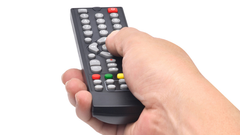 Hand holding a TV remote against a white background