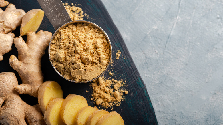 Ginger root ground into bowl, with whole ginger and slices nearby