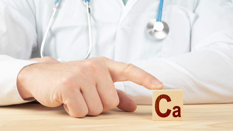 Close up of a doctor's hand using one finger to touch a block with the letters 