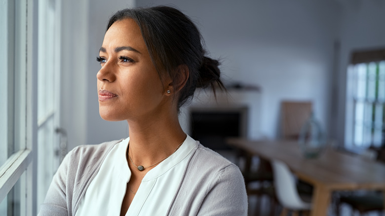 Woman looking out window feeling uncertain