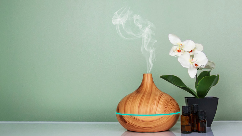 essential oil diffuser with oils, orchid and green background