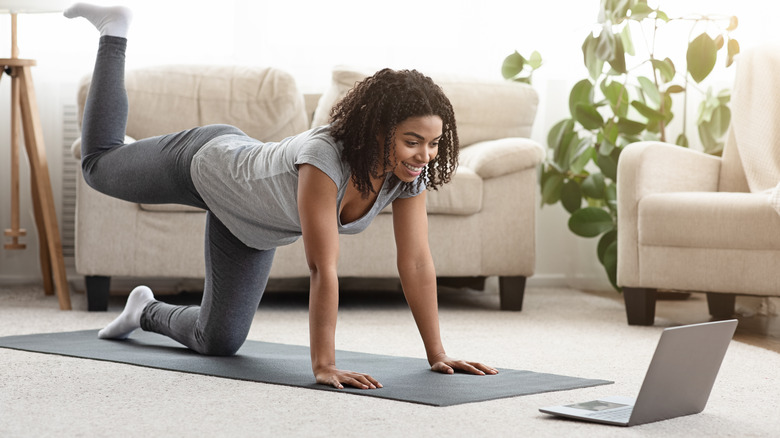 woman exercising to fitness video on laptop