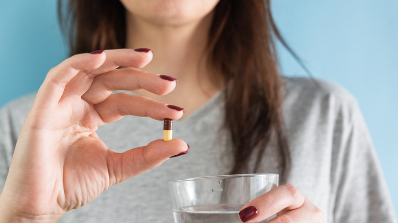 woman holding a pill she is about to take