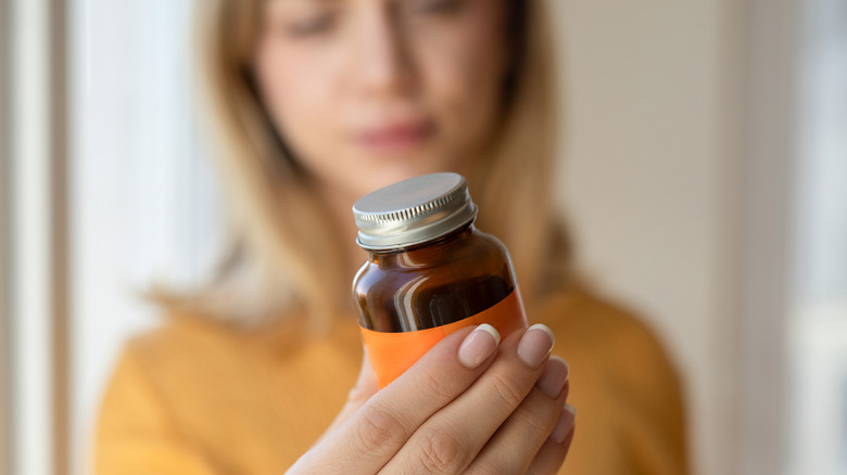 young woman holding a bottle of vitamins or minerals