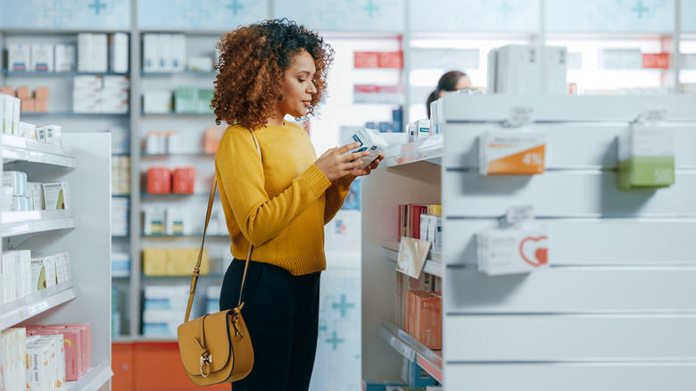 Woman reads medication label in pharmacy